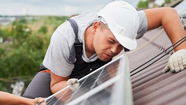 Technician working beside rooftop solar panels